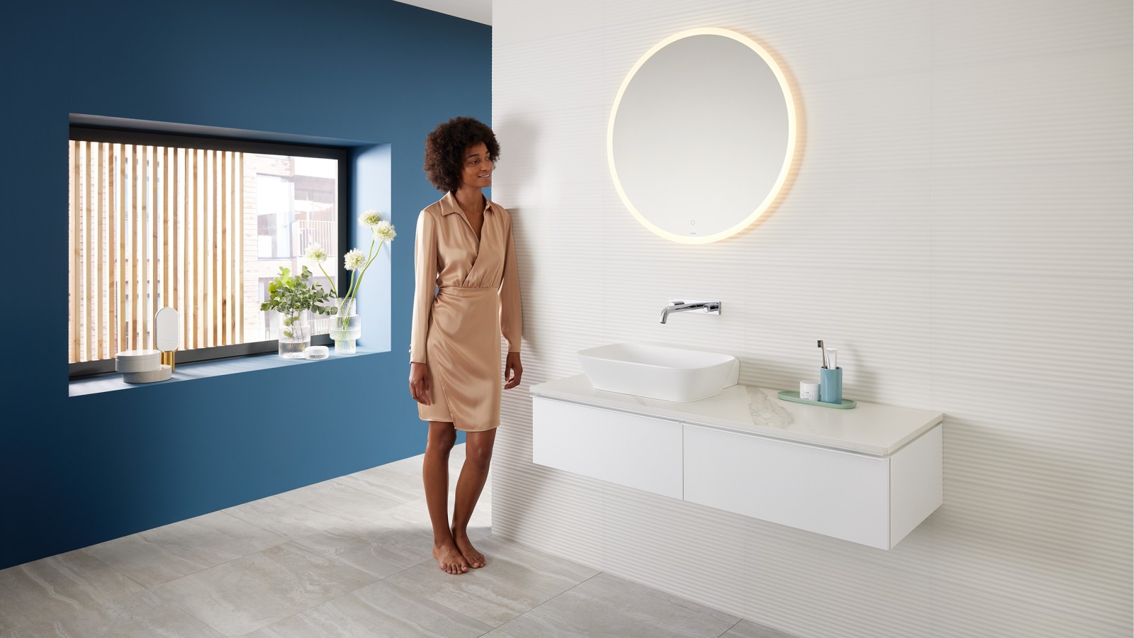 Femme adossée au mur d’une salle de bains moderne combinant des produits de la gamme Geberit Mix & Match Femme adossée au mur d’une salle de bains moderne combinant des produits de la gamme Geberit Mix & Match