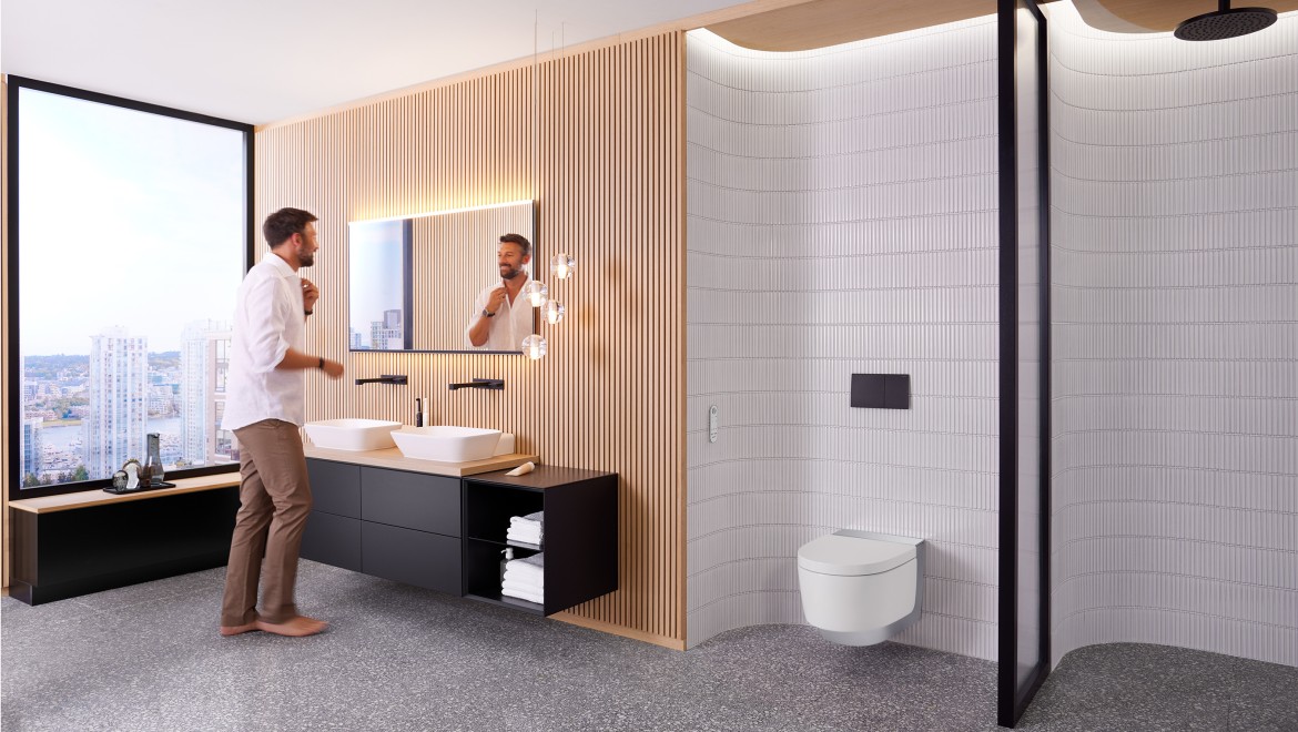 Mann in Badezimmer vor Spiegel Geberit Option Plus Square und schwarzen Geberit ONE Badmöbeln (© Geberit)