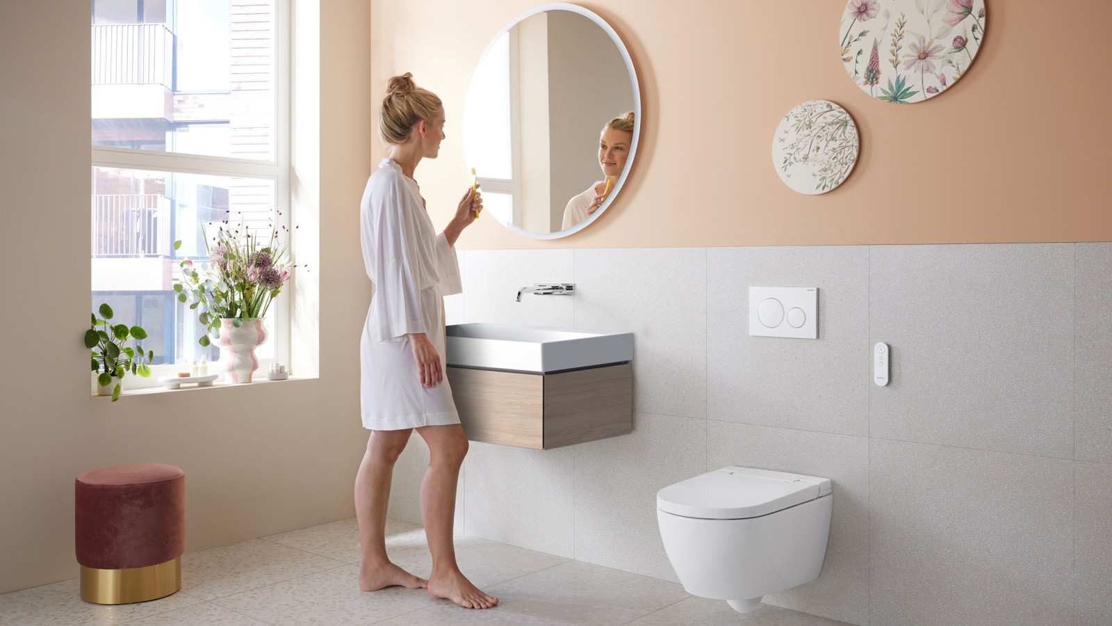 Une femme dans une salle de bains avec Geberit AquaClean Alba, un WC économique avec fonction douchette Une femme dans une salle de bains avec Geberit AquaClean Alba, un WC économique avec fonction douchette