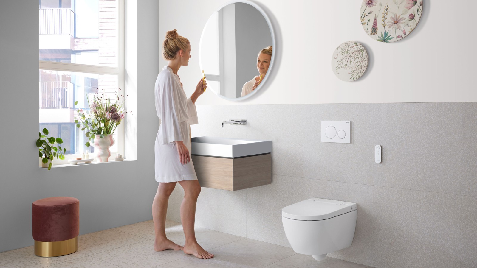 Une femme dans une salle de bains avec Geberit AquaClean Alba, un WC économique avec fonction douchette Une femme dans une salle de bains avec Geberit AquaClean Alba, un WC économique avec fonction douchette