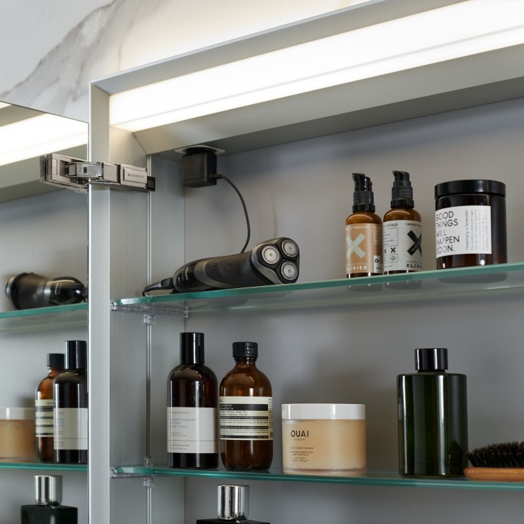 Armoire de toilette Geberit ouverte dans laquelle sont rangés les articles de salle de bains Armoire de toilette Geberit ouverte dans laquelle sont rangés les articles de salle de bains