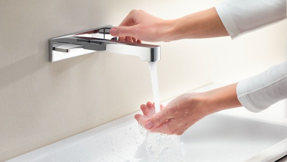 Image macro avec les mains tournant un robinet Geberit ONE et vérifiant le débit et la température de l'eau