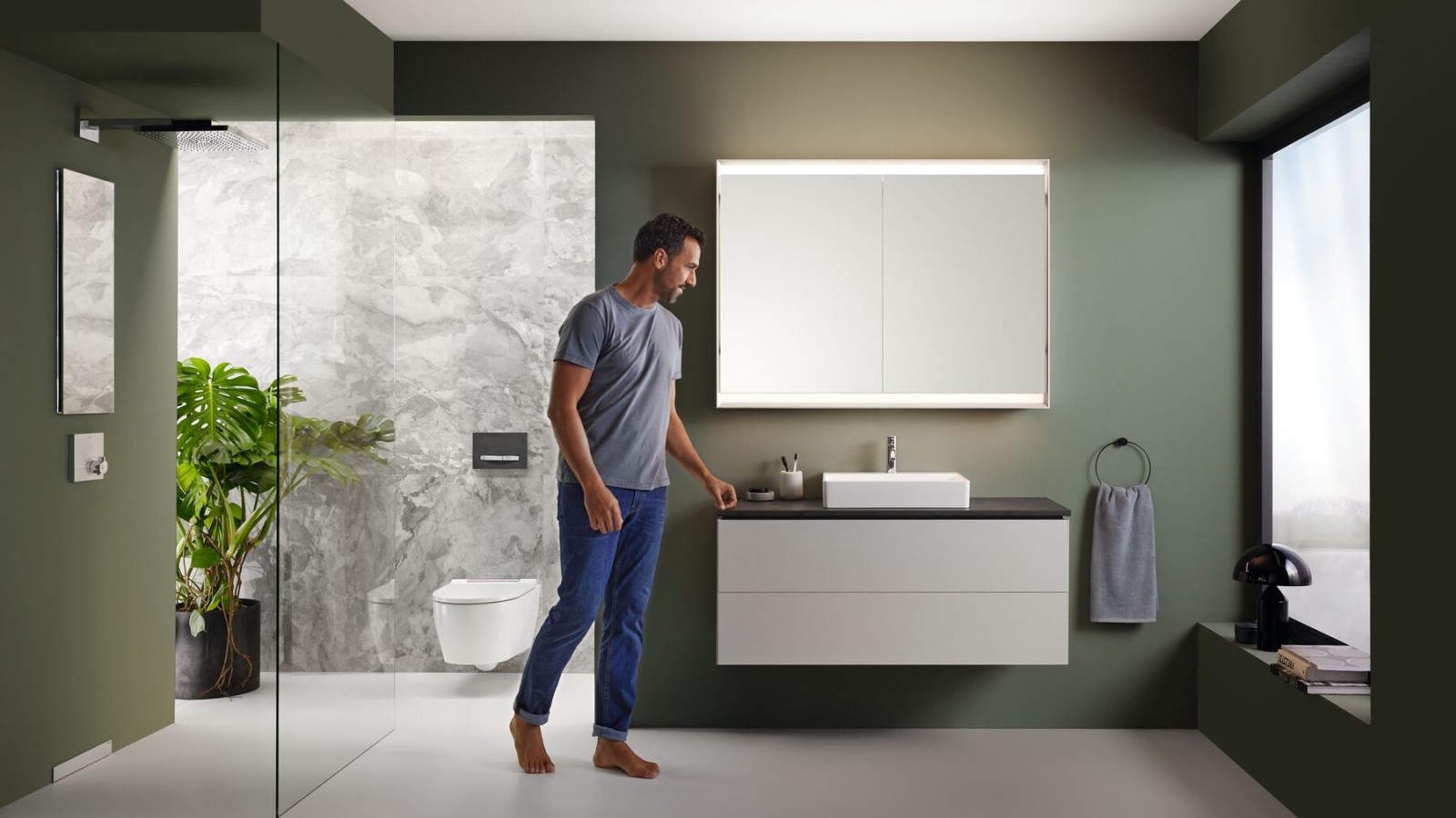 Un homme dans une salle de bains Geberit avec douche de plain-pied Un homme dans une salle de bains Geberit avec douche de plain-pied