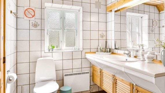 Das ursprüngliche Badezimmer mit bodenstehendem WC, weissen Kacheln und hölzernen Badmöbeln (© @triner2 und @strandparken3)