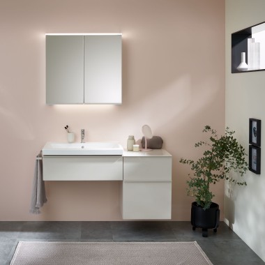 Espace lavabo avec meubles de salle de bains, lavabo et armoire à glace de Geberit sur un mur aux couleurs pastel