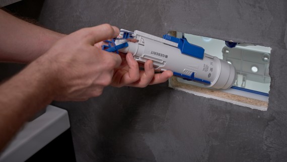 Un homme installe un mécanisme de chasse Geberit dans un réservoir à encastrer (© Ben Huggler) Un homme installe un mécanisme de chasse Geberit dans un réservoir à encastrer (© Ben Huggler)