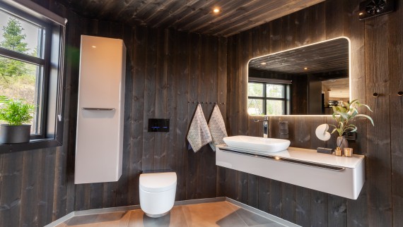 Auch das Bad ist mit Holz ausgekleidet, nebst dem AquaClean Dusch-WC Mera finden sich hier auch diverse andere Geberit Produkte vor der Wand (© Geberit) Auch das Bad ist mit Holz ausgekleidet, nebst dem AquaClean Dusch-WC Mera finden sich hier auch diverse andere Geberit Produkte vor der Wand (© Geberit)