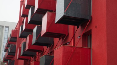 Une façade rouge vif avec des balcons cubiques à l'avant est le nouveau point d'attraction de la Goldsteinstrasse à Francfort-sur-le-Main (DE) (© Geberit)