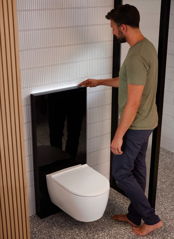 Homme à côté d’un Geberit Monolith Plus avec ComfortLight Homme à côté d’un Geberit Monolith Plus avec ComfortLight