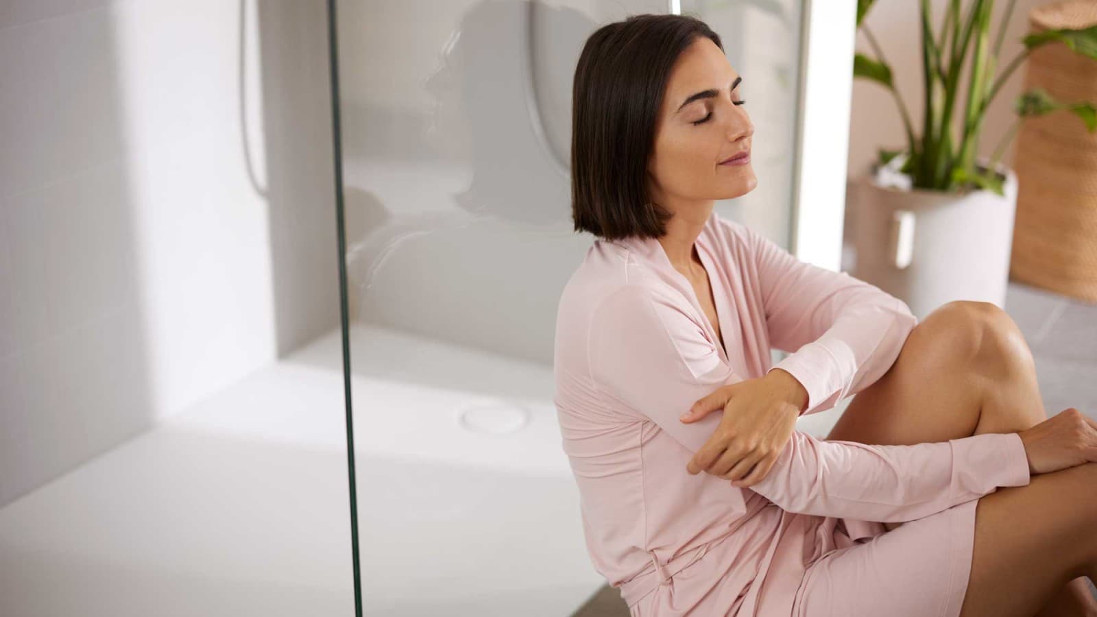 Frau sitzt im Badezimmer vor der Dusche Frau sitzt im Badezimmer vor der Dusche